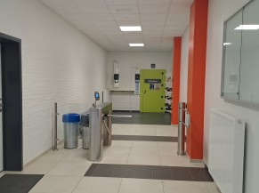 Couloir vers les vestiaires avec barrière de contrôle et zone de  déchaussage