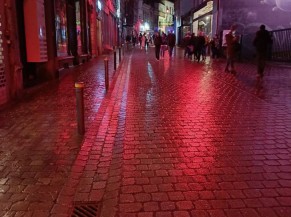 Rue avec potelets marqués et éclairage public gelatiné en rouge servant de ligne guide