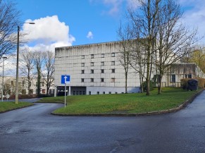 Vue extérieure du centre sportif, avec voie d'accès vers l'entrée de la piscine